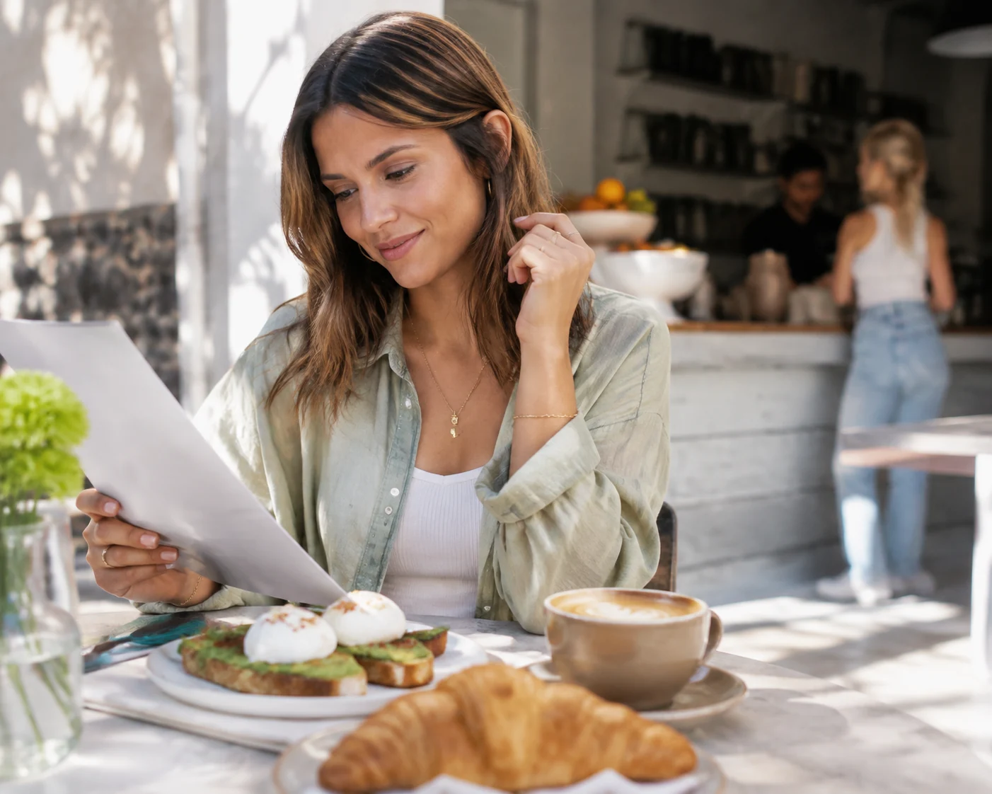 Guest at sunlit cafe table selecting from fresh breakfast dishes.