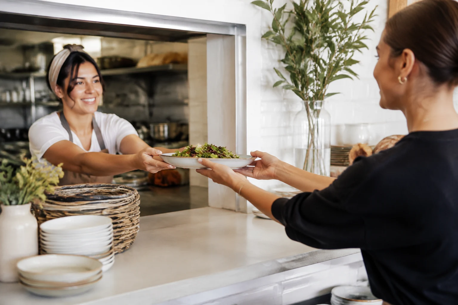Cafe team seamlessly passing a tray from prep area to front counter.