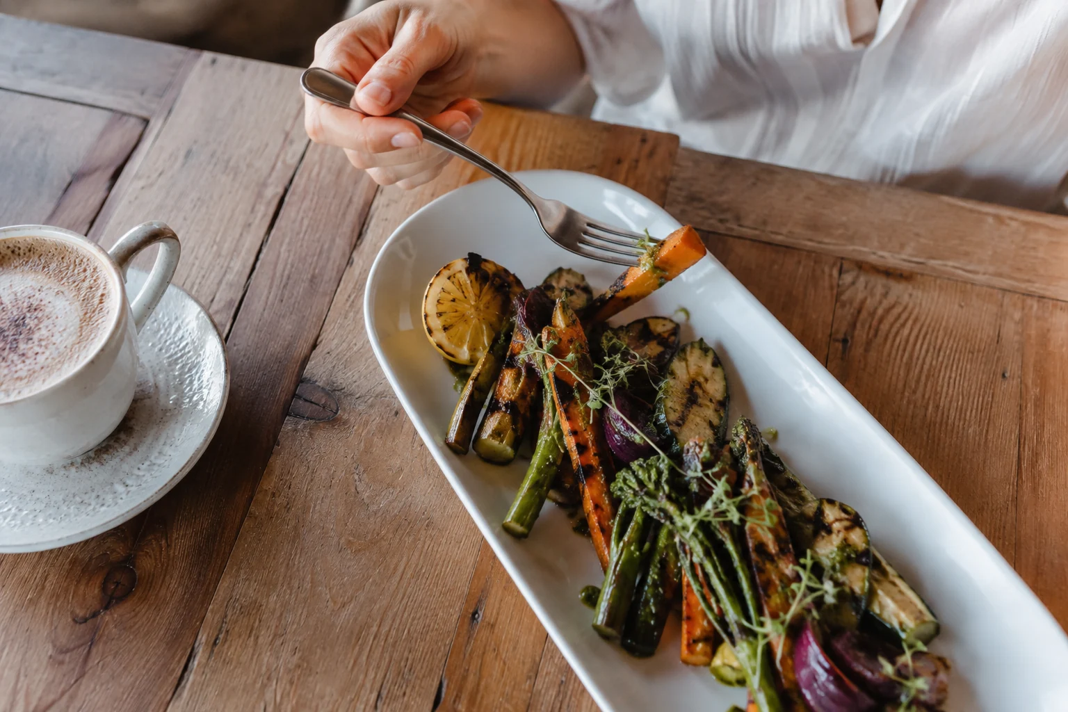 Overhead long ceramic plate of fresh grilled vegetables.